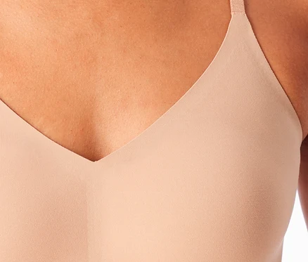 Eine Person trägt ein SCHIESSER Invisible Bustier mit Pads in Maple-Farbe, sichtbar sind der V-Ausschnitt und ein Träger.