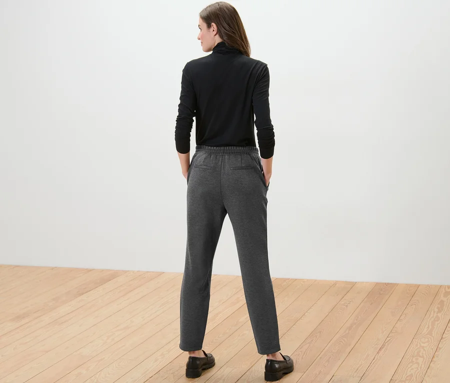 Frau von hinten trägt ein schwarzes Langarmshirt und graue Joggpants.