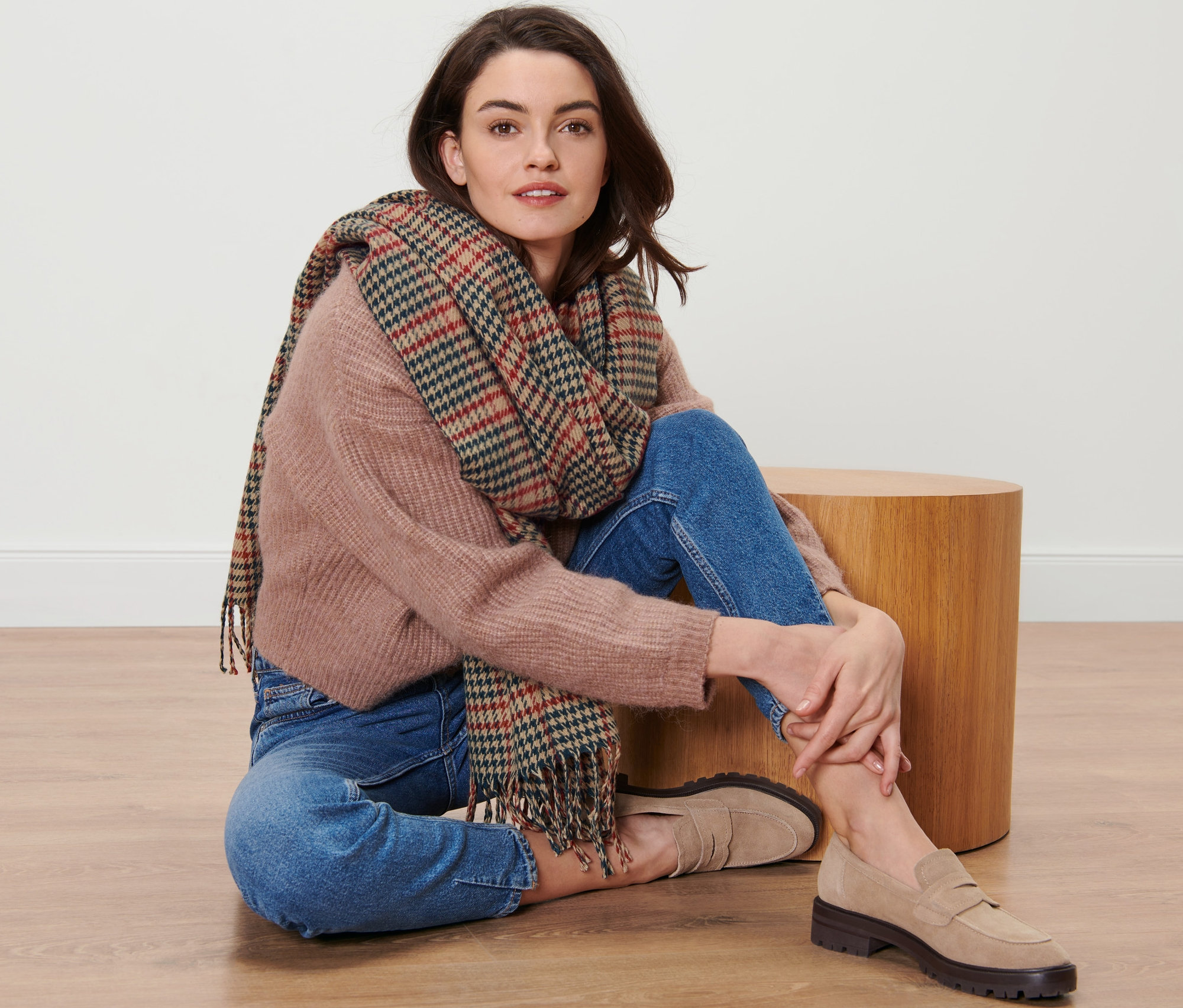 Frau sitzt auf dem Boden und trägt einen karierten Webschal.
