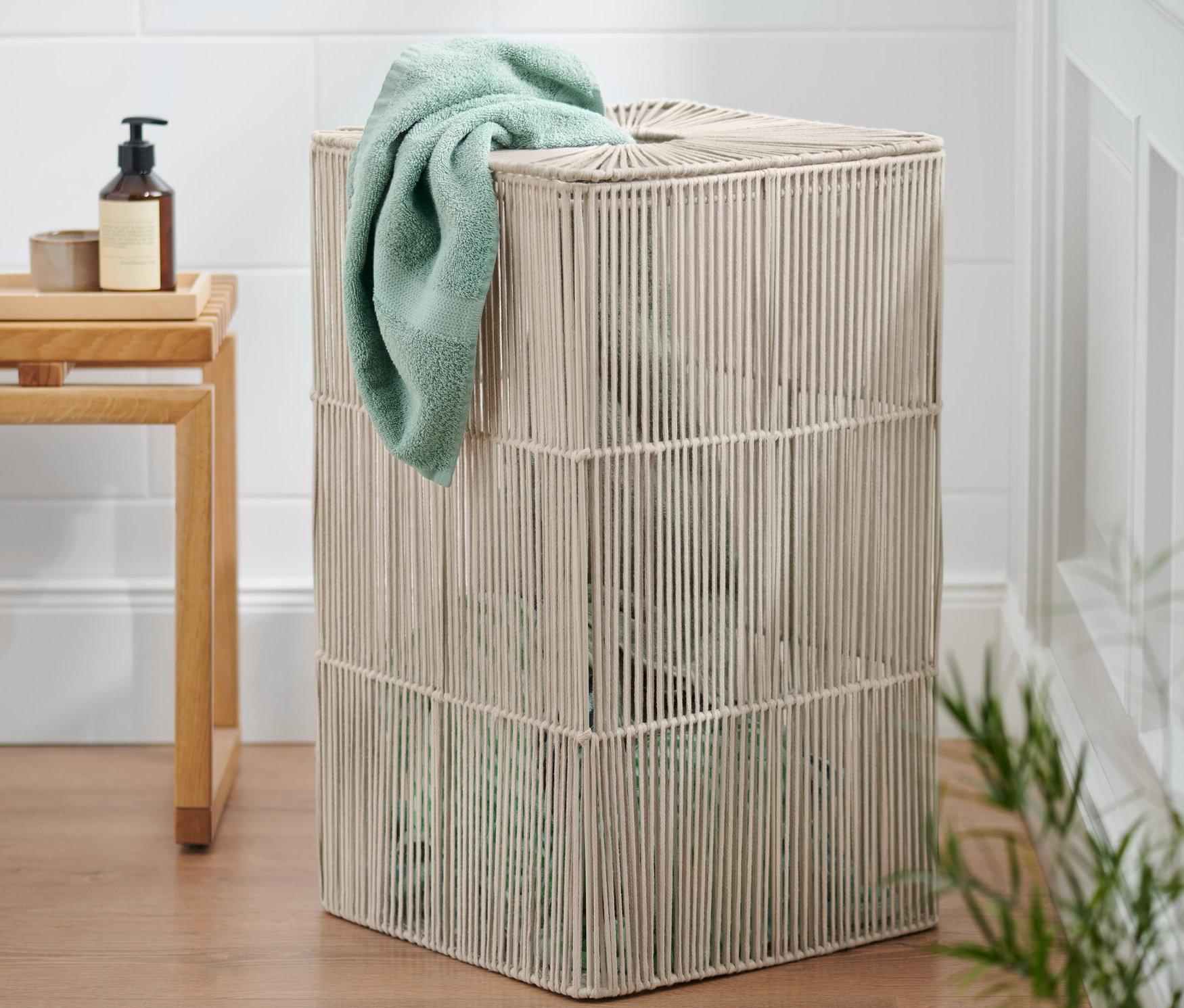 Eine Wäschetonne mit einem grünlichen Handtuch, das über den Rand hängt.