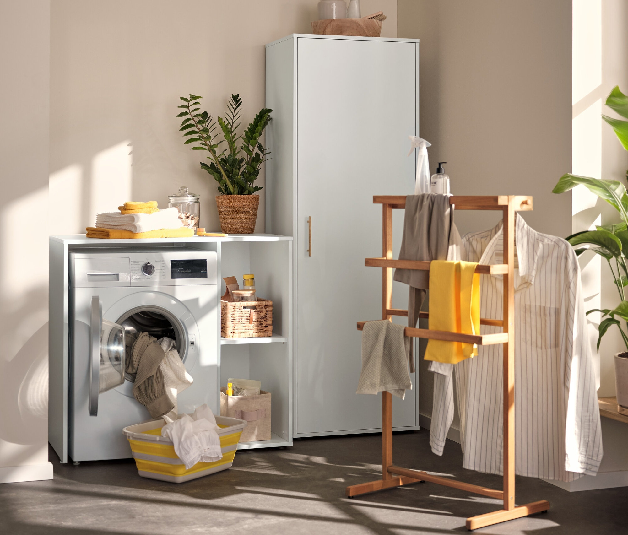 Im Waschraum stehen ein Universalschrank, ein Waschmaschinenregal mit seitlichem Stauraum und ein Stummer Diener.