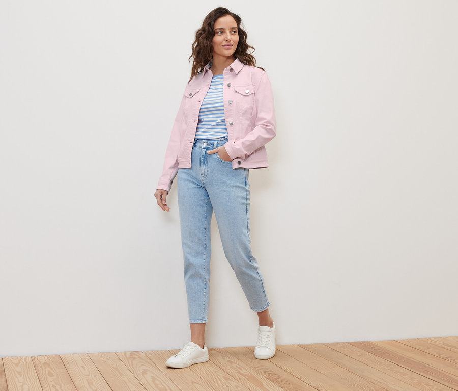 Frau posiert in Jeansjacke und hellblauen Jeans.