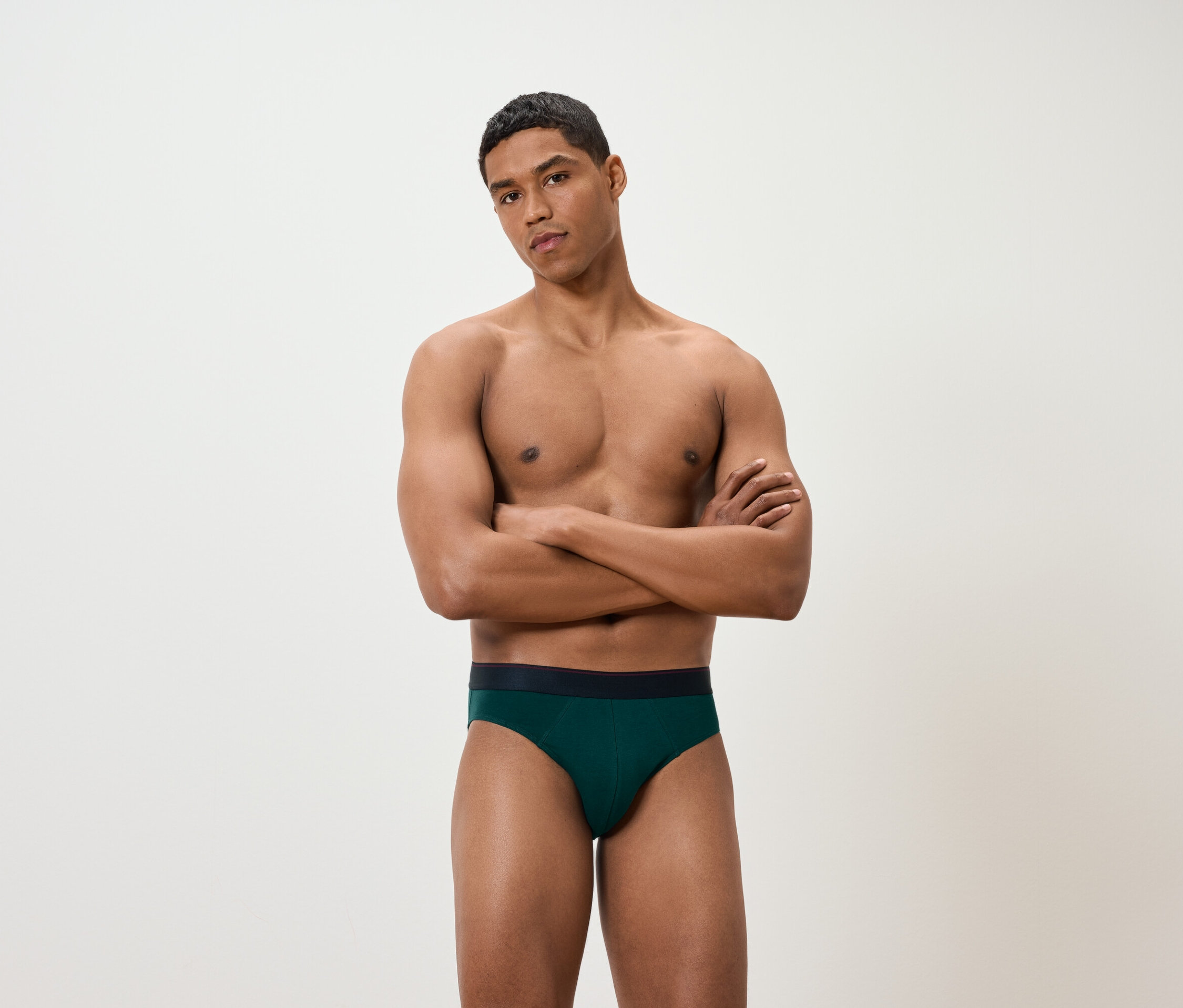 Mann mit verschränkten Armen trägt grüne Slips.