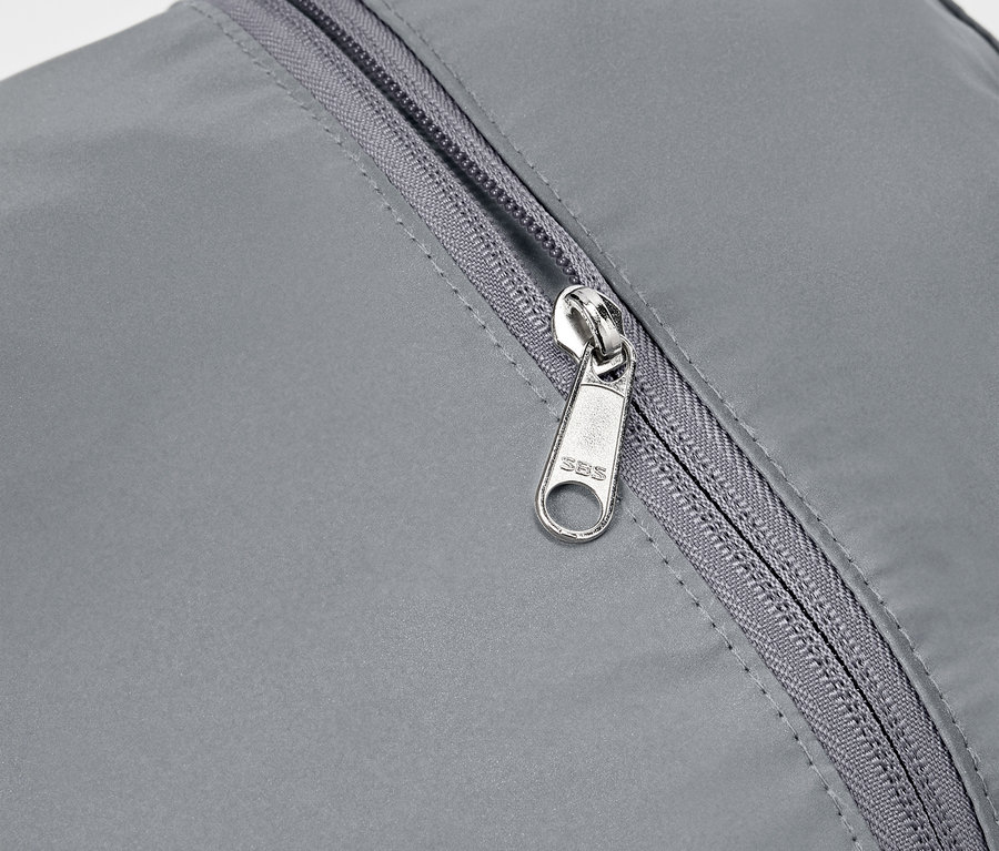 Detailaufnahme eines grauen reflektierenden Rucksacks mit silbernem Reißverschluss.