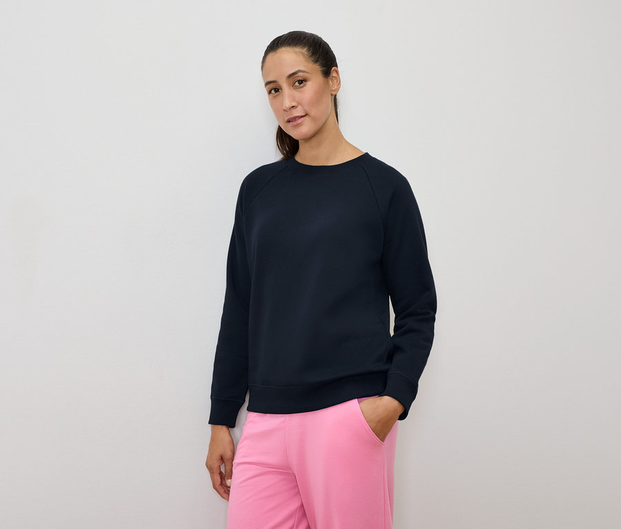 Frau in marineblauem Sweatshirt und pinkfarbener Hose.