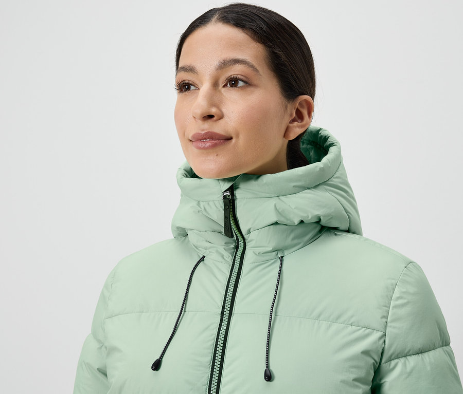 Frau trägt eine hellgrüne Steppjacke.