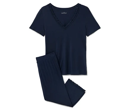 Ein marineblauer Pyjama mit Spitzenbesatz liegt auf einem weißen Hintergrund.