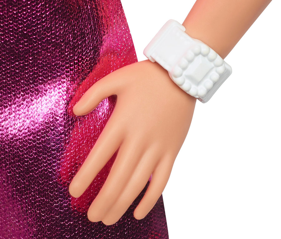 Nahaufnahme der Hand einer Puppe, die ein pinkfarbenes, paillettenbesetztes Kleid und eine weiße Armbanduhr trägt.