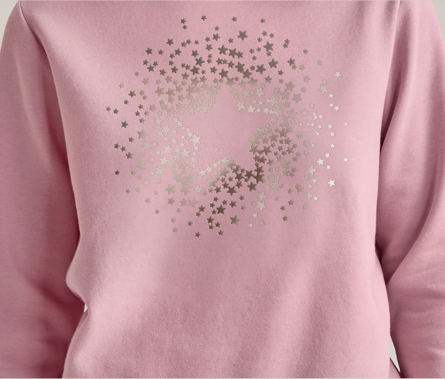 Nahaufnahme eines rosa Sweatshirts mit langen Ärmeln, das auf der Vorderseite ein großes silbernes Sternenmuster aus vielen kleineren Sternen zeigt.