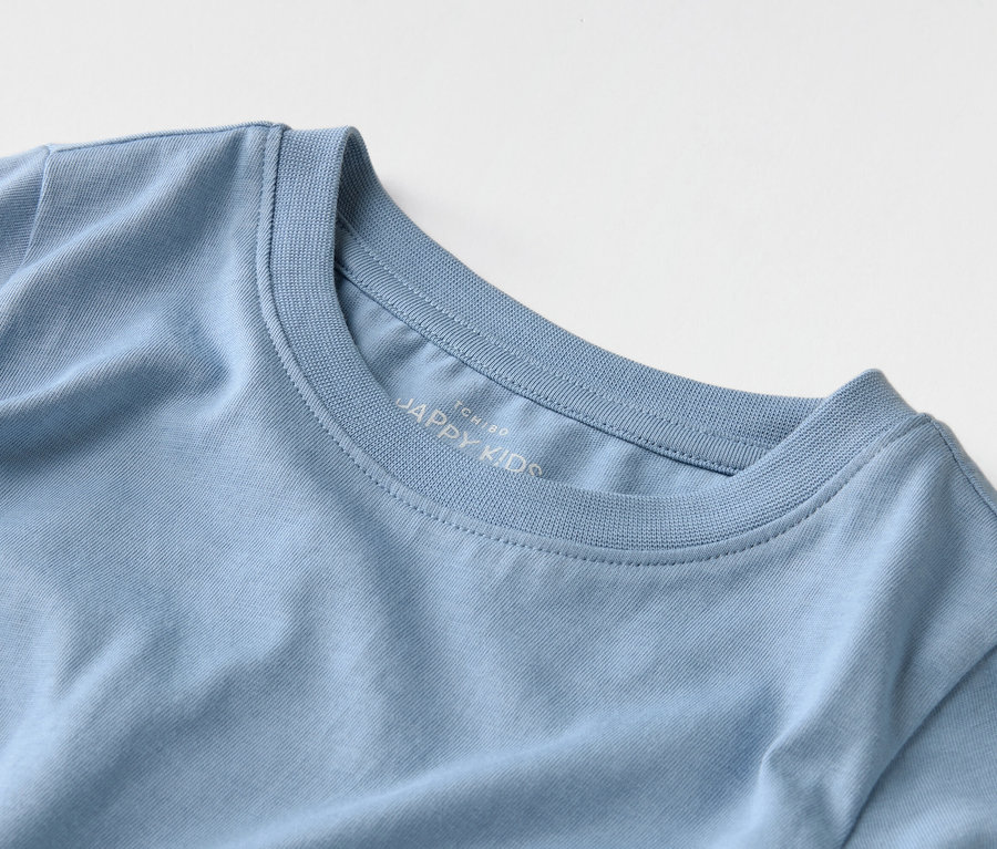Nahaufnahme eines hellblauen T-Shirts mit der Aufschrift "JAPPY KIDS" auf dem Kragen.