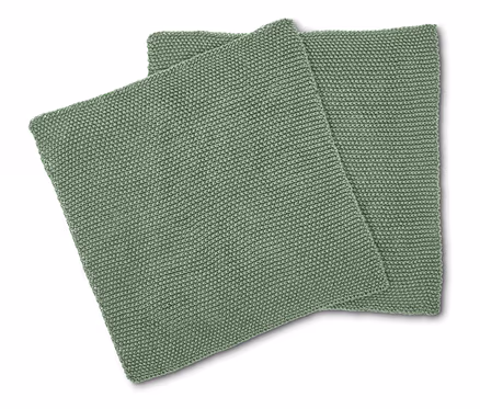 Zwei quadratische, hellgrüne Kissen mit Strickmuster liegen übereinander.