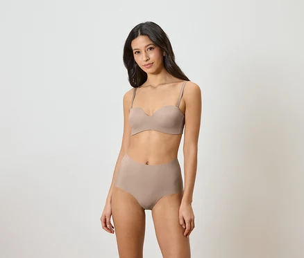Frau trägt einen trägerlosen BH und hochtaillierte Slips in Beige.