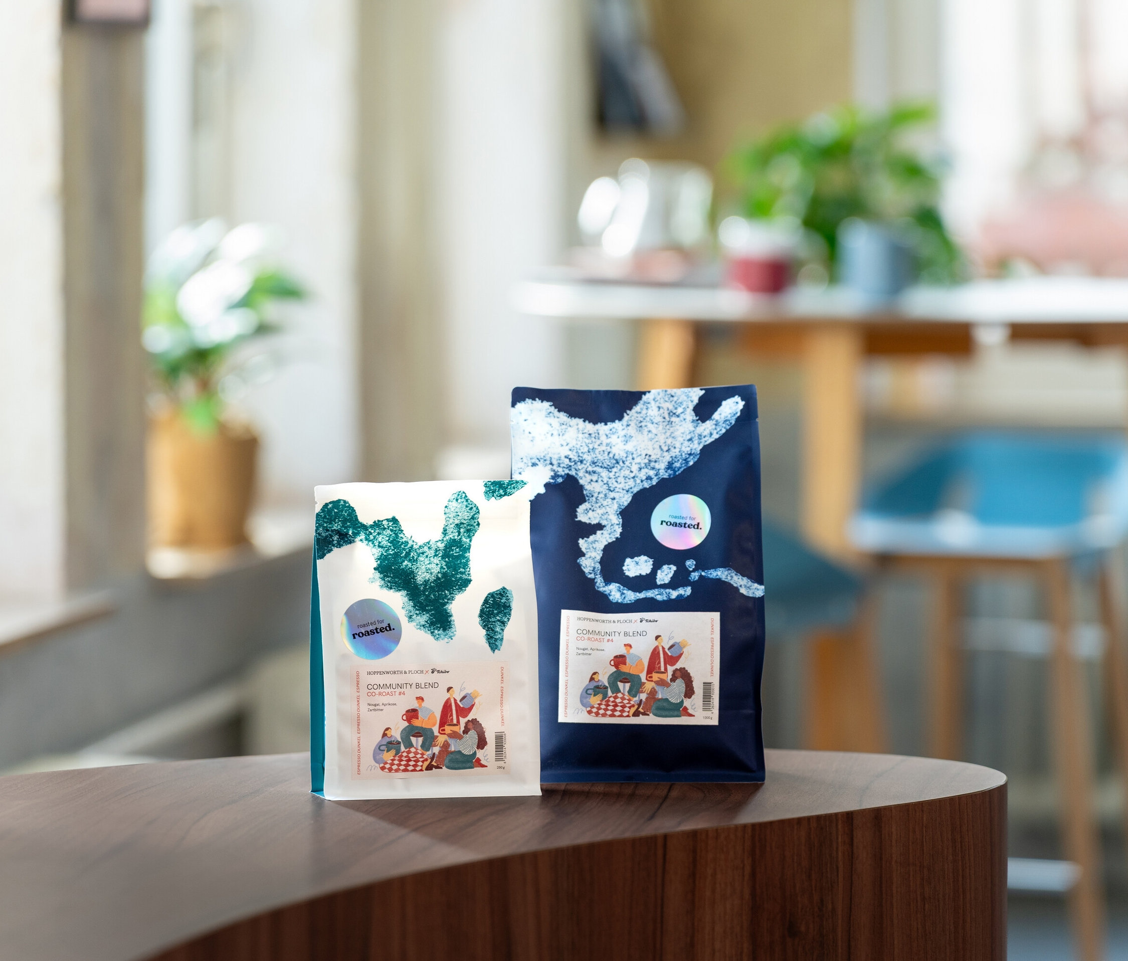 Zwei Kaffeepackungen stehen auf einem Tisch, eine weiße und eine blaue.