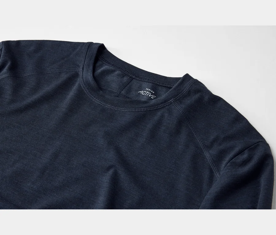 Nahaufnahme eines dunkelblauen Langarmshirts mit Rundhalsausschnitt und sichtbaren Nähten, das ein weißes „TCHIBO ACTIVE“-Etikett am inneren Kragen zeigt.