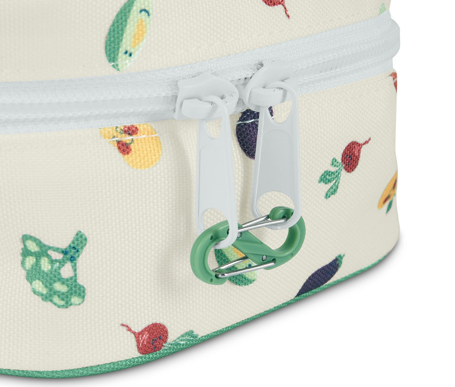 Detailansicht einer Medikamententasche mit Kindersicherung, Gemüseaufdruck, weißem Reißverschluss und grünem Karabiner.