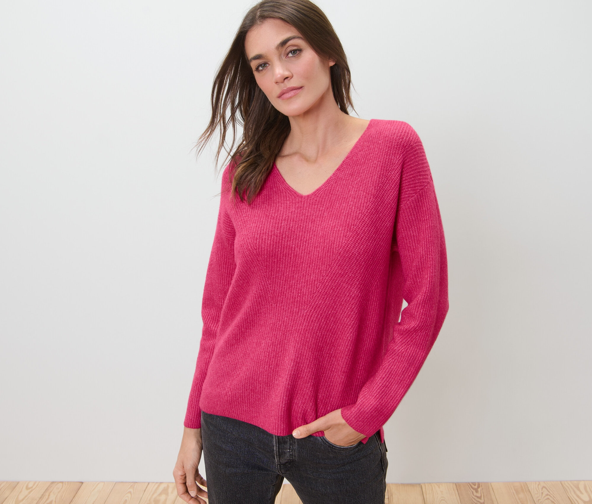 Frau posiert in himbeerfarbenem Grobstrickpullover.