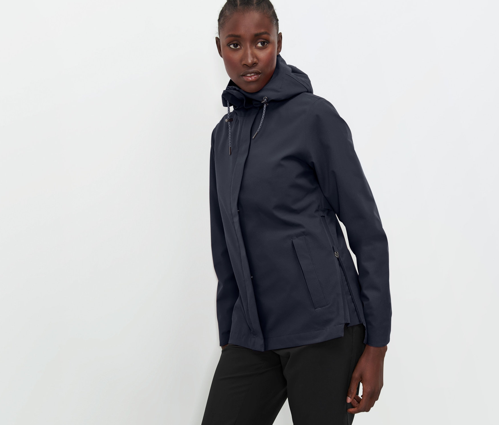 Frau posiert in marineblauer Funktions-Outdoorjacke und schwarzer Hose.