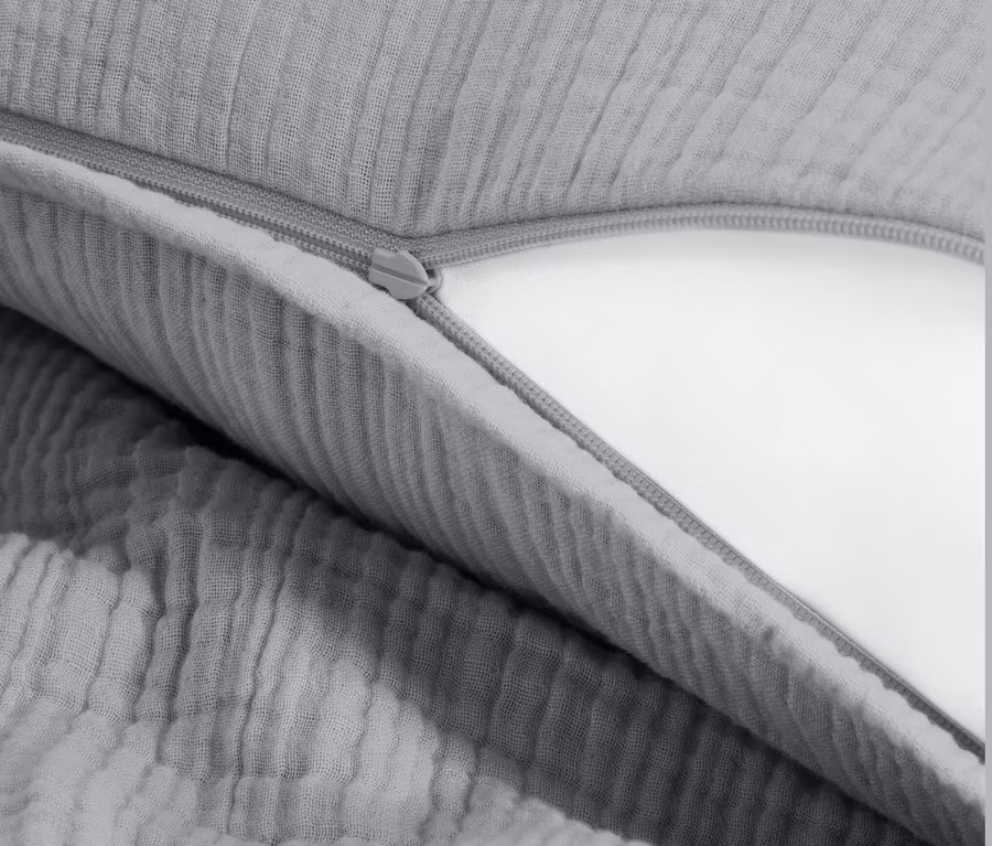 Detailaufnahme von grauer Musselin-Bettwäsche mit Reißverschluss.