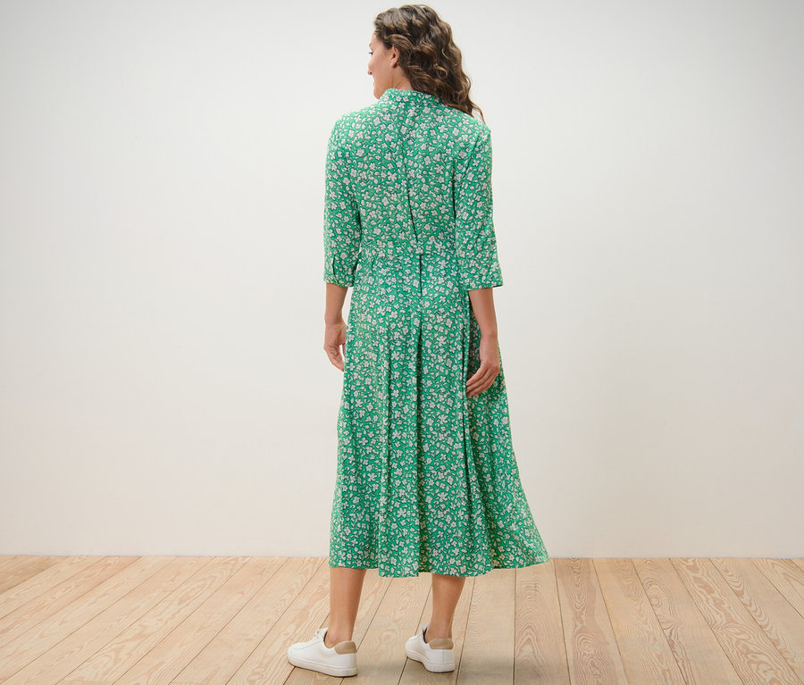 Frau von hinten in einem grünen, bedruckten Hemdblusenkleid.