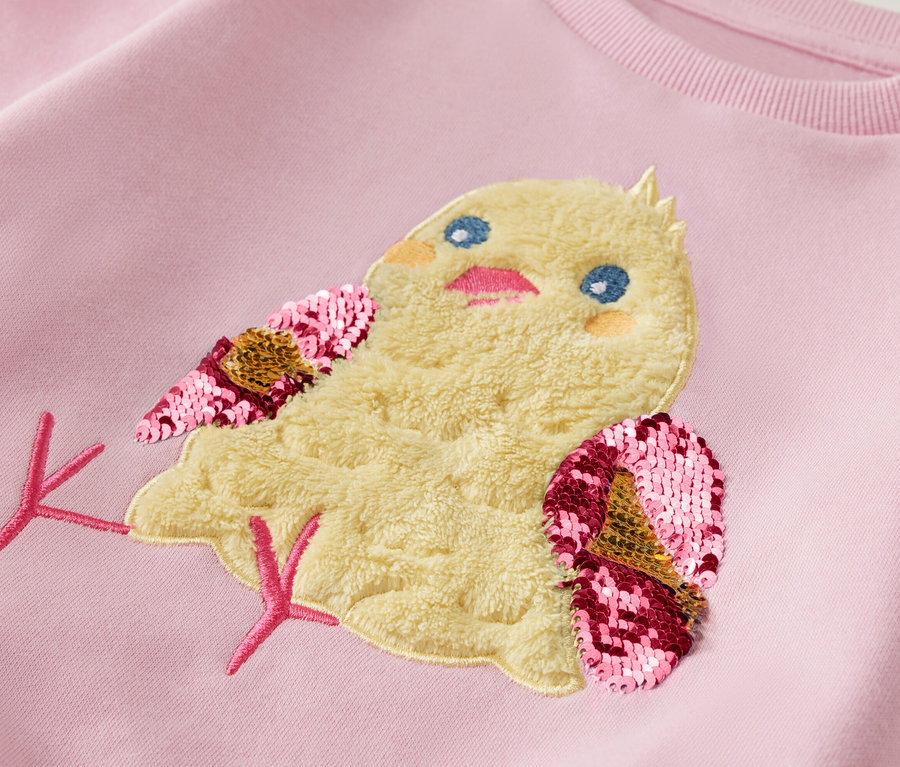 Hellrosa Kinder-Sweatshirt mit einem Küken-Aufnäher mit Paillettenflügeln.