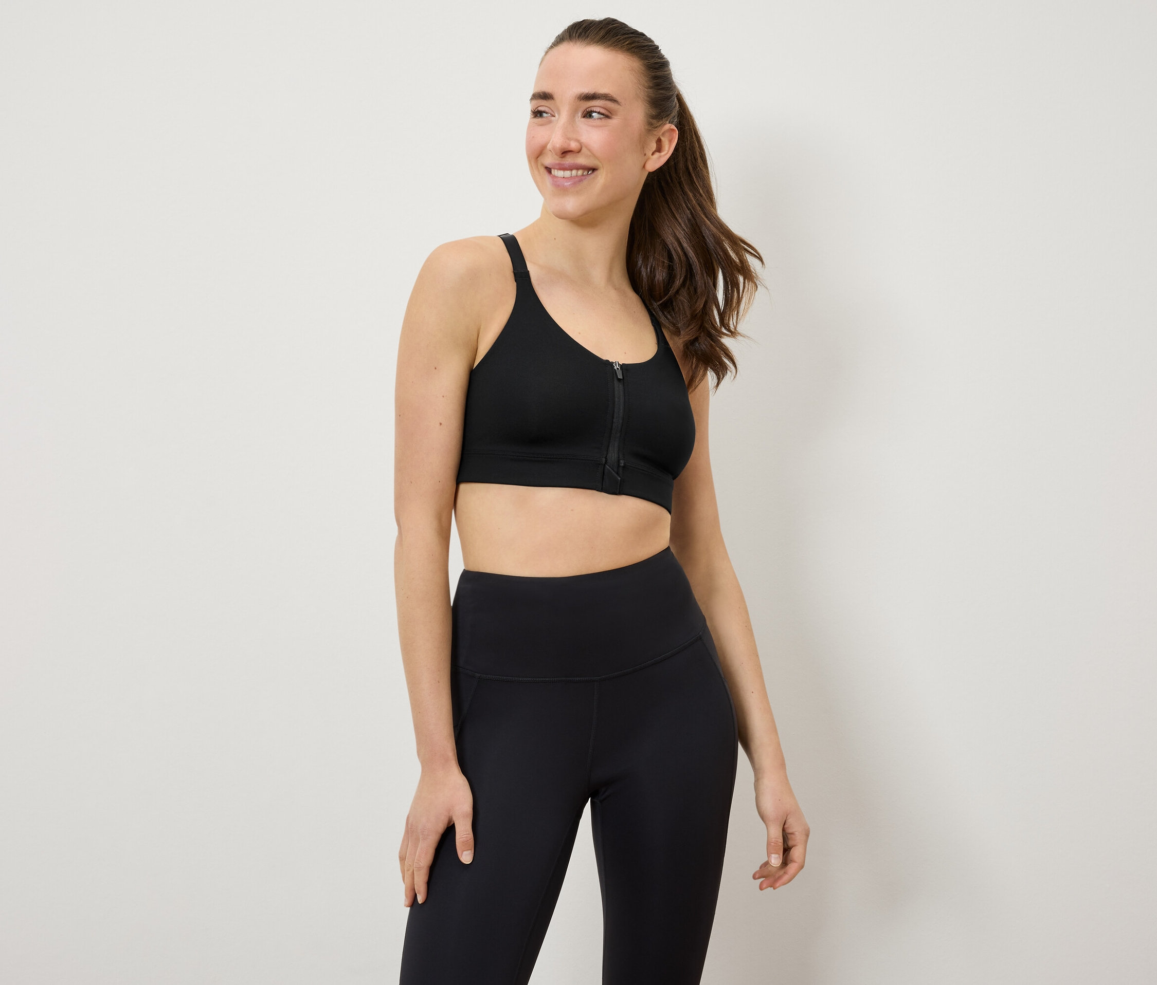 Frau trägt einen schwarzen Sport-BH und Leggings.