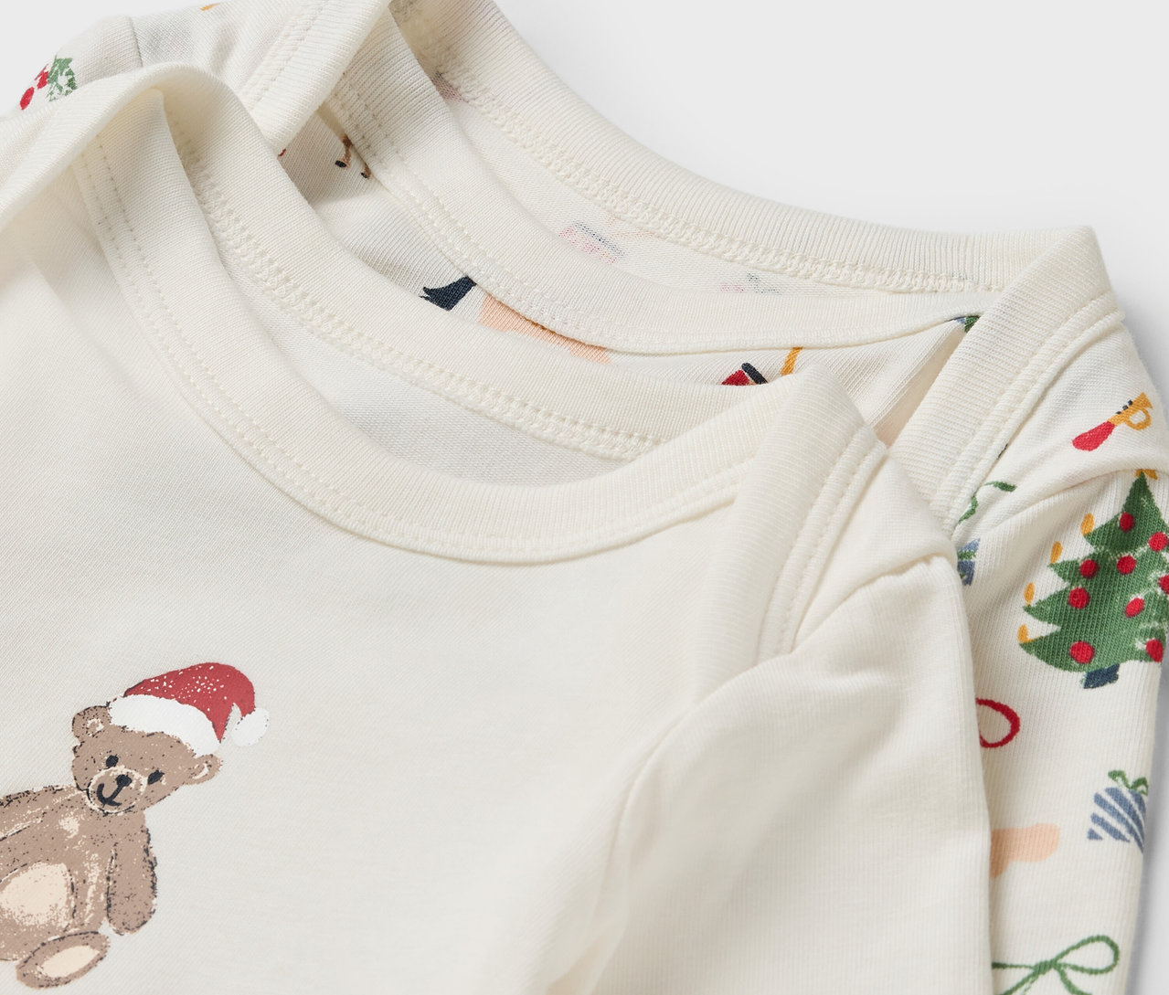 Zwei weiße Baby-Langarmbodys mit Weihnachtsmotiven.