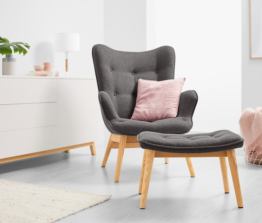 Dunkelgrauer Einzelsessel mit Fußhocker in einem Wohnzimmer.
