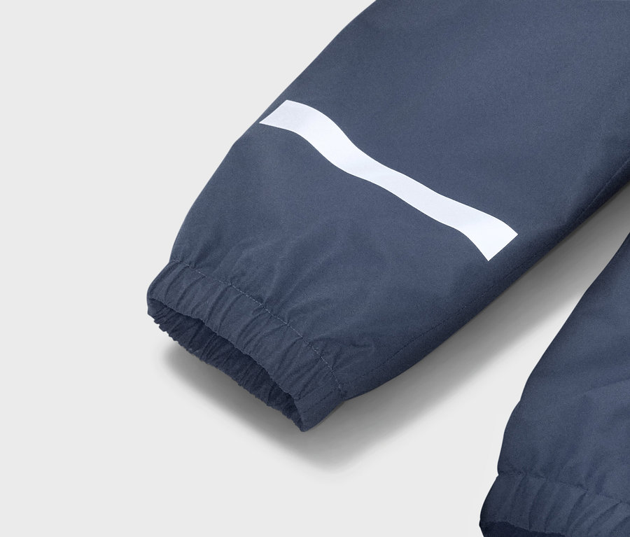 Detailansicht eines blauen Jackenärmels mit einem weißen, wellenförmigen Streifen und einem elastischen Bündchen.