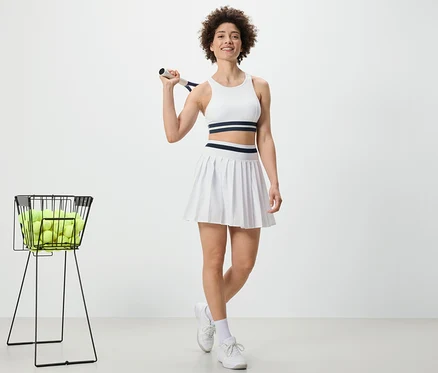 Frau hält Tennisschläger und trägt Sportrock.