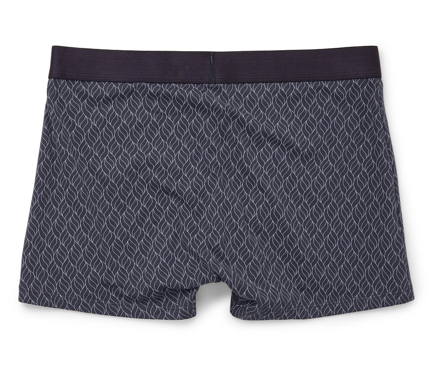 Nahaufnahme von Boxershorts mit blauem Muster und dunklem Bund, liegend auf einem weißen Hintergrund.