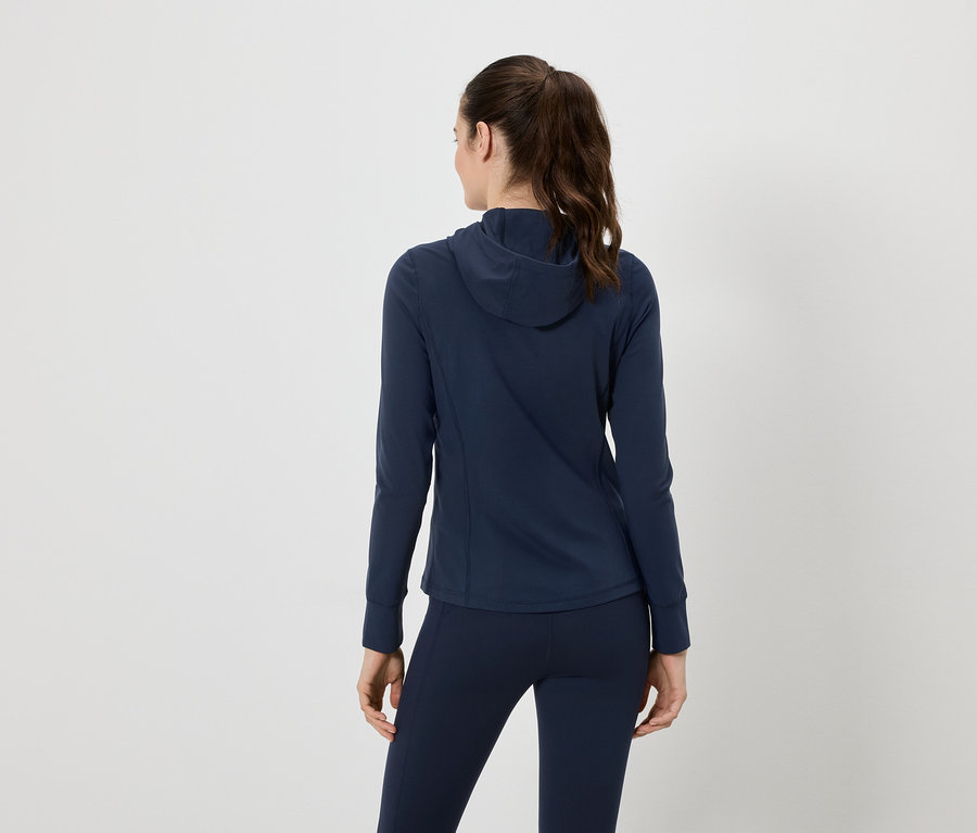 Rückansicht einer Frau mit Pferdeschwanz, die einen marineblauen Trainingsanzug mit Kapuzenjacke und Leggings trägt.