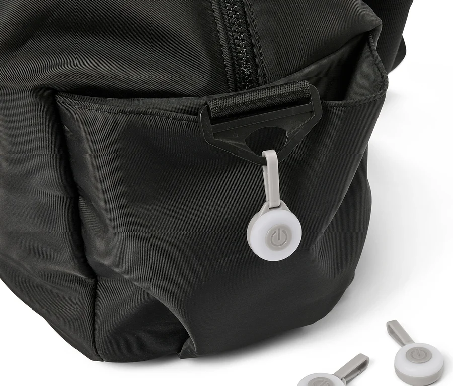 Nahaufnahme einer schwarzen Tasche mit einem angebrachten, runden, grauen Licht und zwei weiteren Lichtern im Vordergrund.
