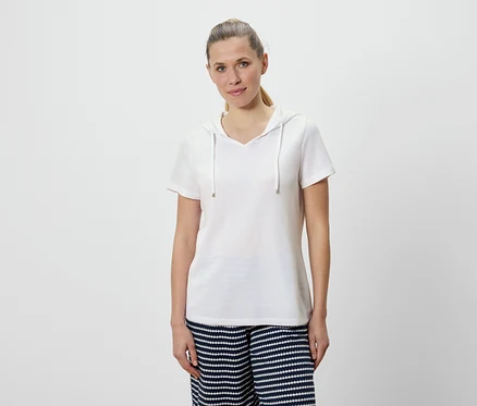 Frau trägt ein weißes Kapuzen-T-Shirt und eine blau-weiß gestreifte Hose.