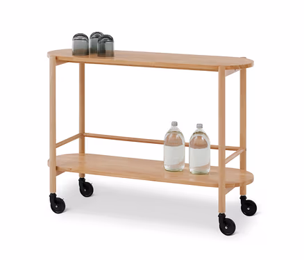 Ein ovaler Servierwagen aus hellem Holz mit zwei Ablagen. Auf der oberen Ablage stehen drei umgedrehte dunkle Gläser, auf der unteren zwei Wasserflaschen. Der Wagen hat schwarze Rollen.