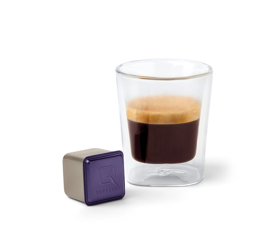 Eine Qbo Espresso CAFEZINHO DO BRASIL Kapsel steht neben einem Glas Espresso.