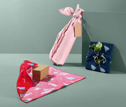 Drei Geschenke, verpackt in Stoff-Geschenkpapier in verschiedenen Farben.
