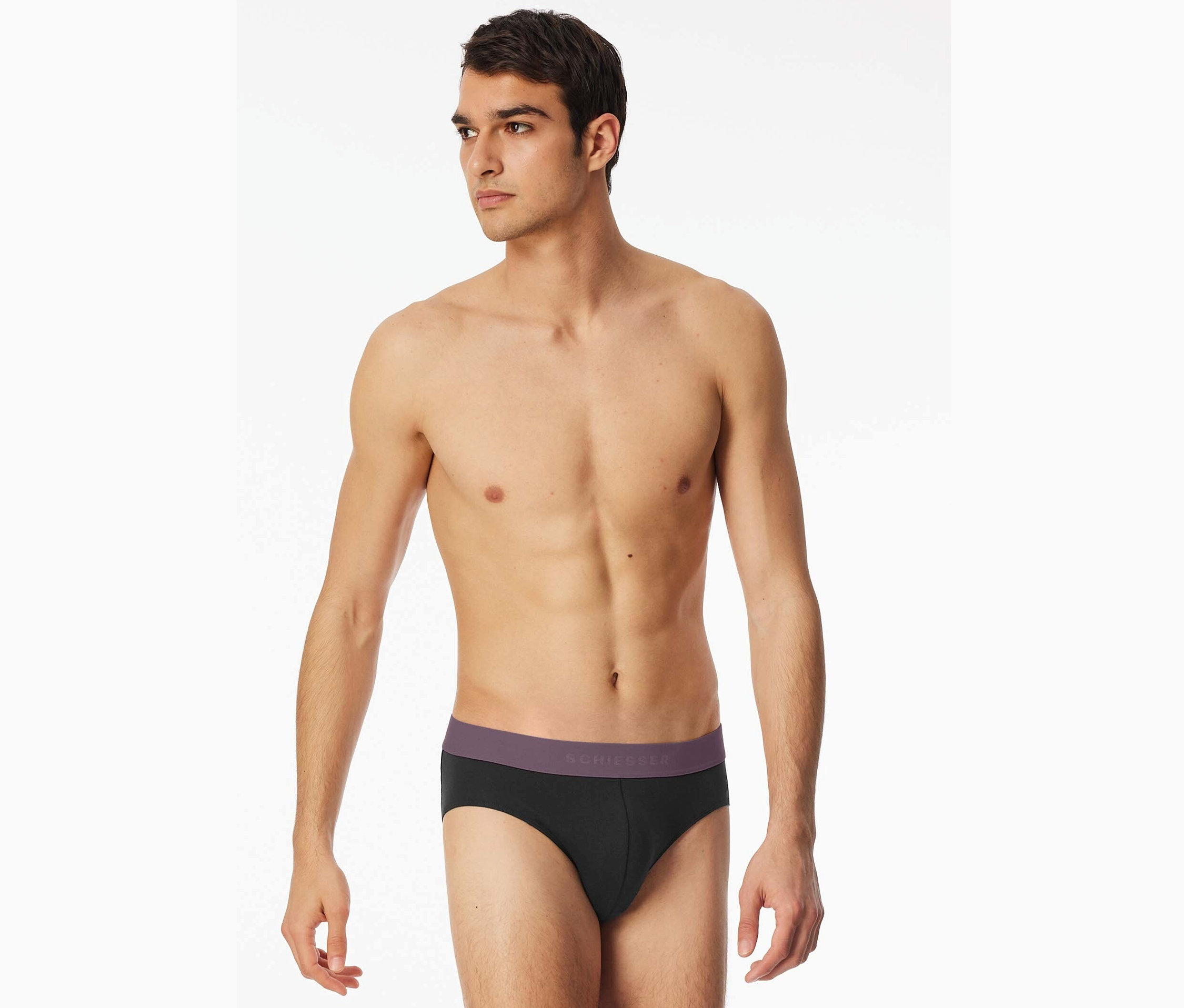 Mann mit freiem Oberkörper trägt schwarze Schiesser Slips mit lila Bund.