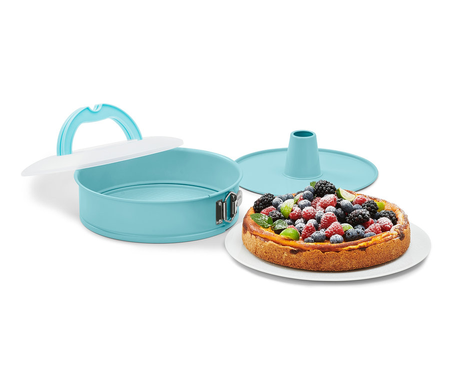 Türkise Springform mit Transportdeckel neben einem Kuchen mit Früchten.