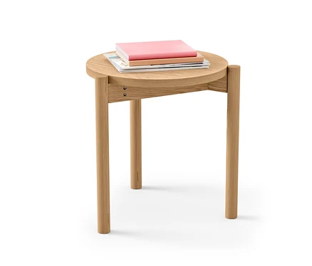 Ein runder Beistelltisch aus Holz mit drei Büchern darauf.