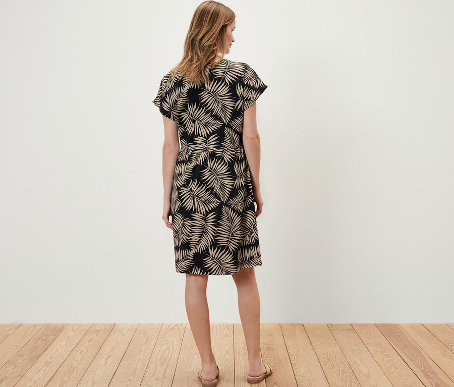 Eine Frau steht mit dem Rücken zur Kamera und trägt ein bedrucktes Jerseykleid.