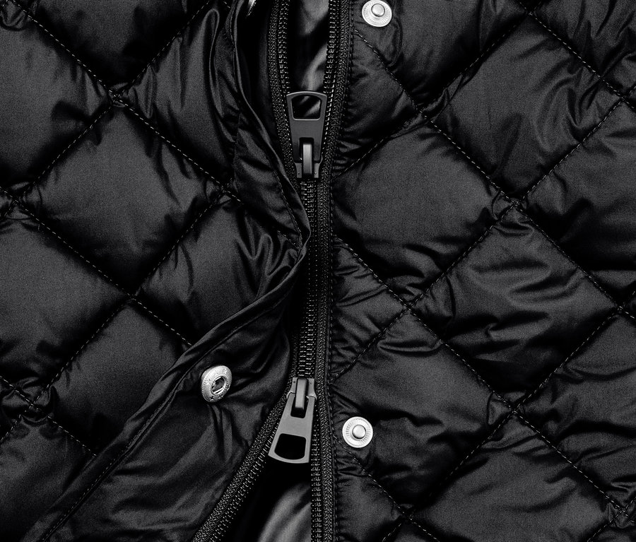 Detailaufnahme einer langen, schwarzen Steppweste mit Kapuze und offenem Reißverschluss.
