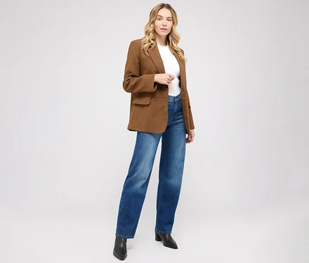 Frau posiert in Angels Jeans »Liz« Wide Leg, mid blue used, einem weißen T-Shirt und einem braunen Blazer.