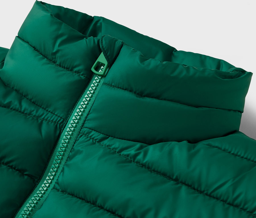 Detailaufnahme einer gesteppten, grünen Jacke mit Kragen und Reißverschluss.