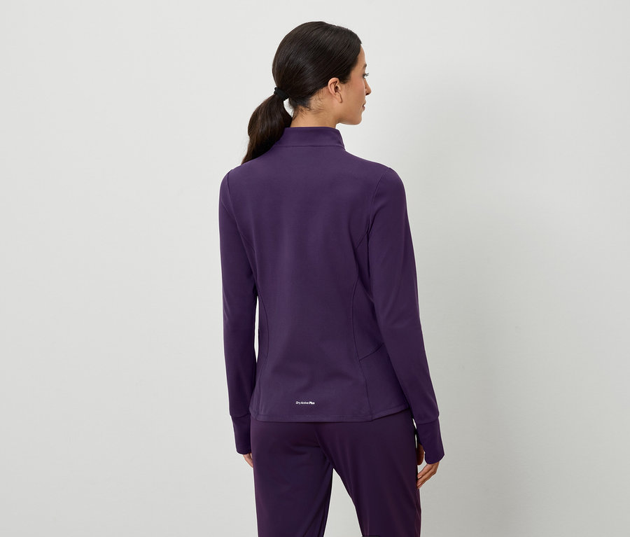 Rückansicht einer Frau mit braunen, zum Pferdeschwanz gebundenen Haaren, die eine violette Jacke und Hose trägt.