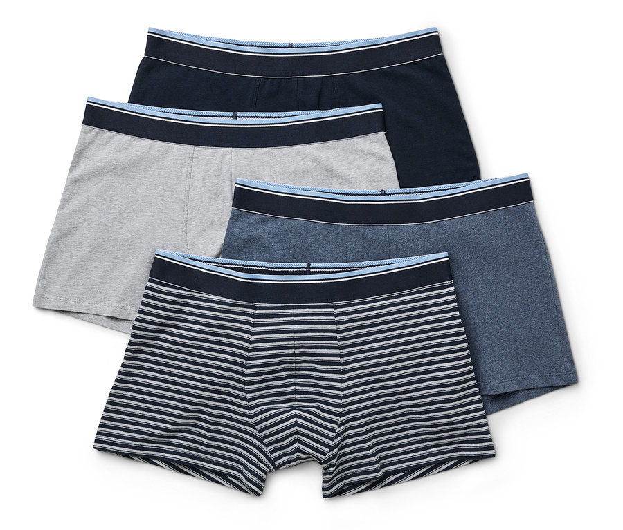Vier Herren Boxershorts in Dunkelblau, Grau, Blau und Blau-Weiss liegen übereinander.