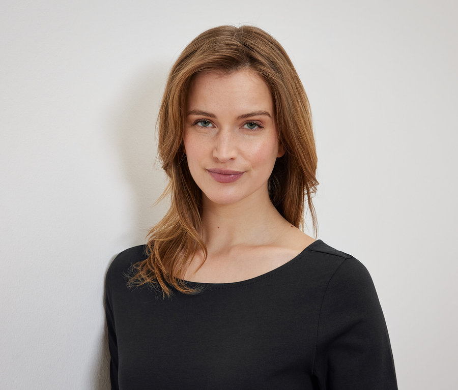 Porträt einer Frau mit braunen Haaren in einem schwarzen T-Shirt.