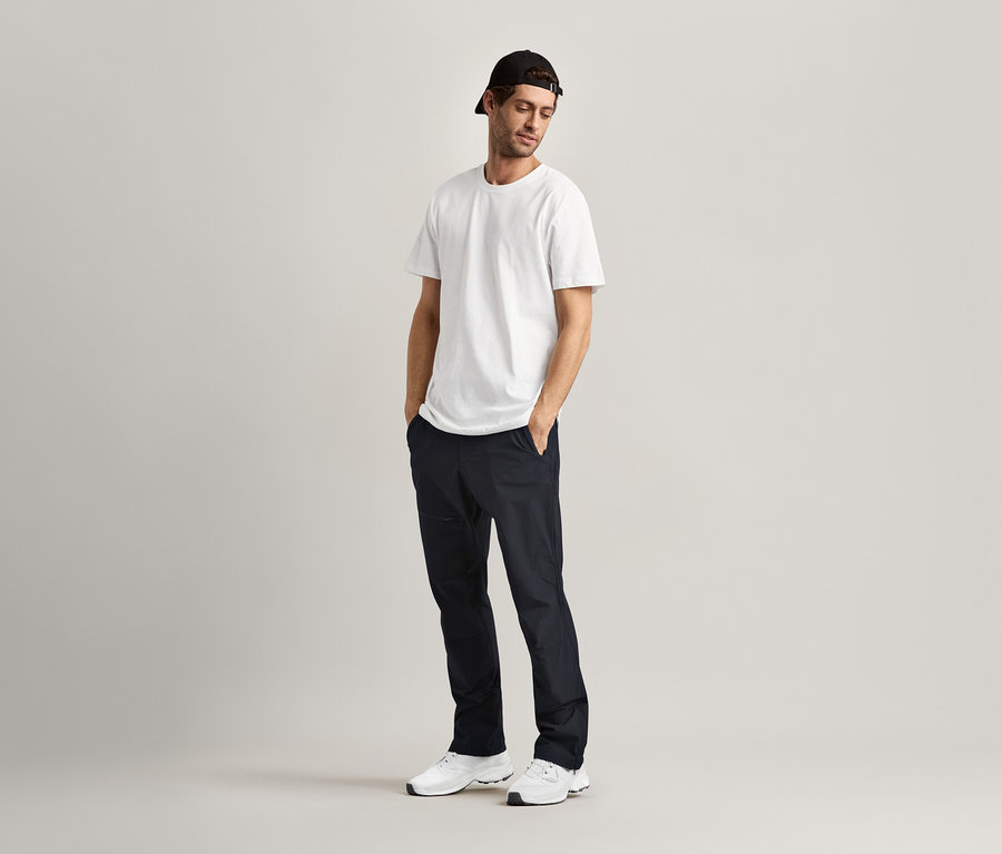 Mann steht mit Händen in den Hosentaschen und trägt 2 T-Shirts mit Rundhalsausschnitt, weiß.