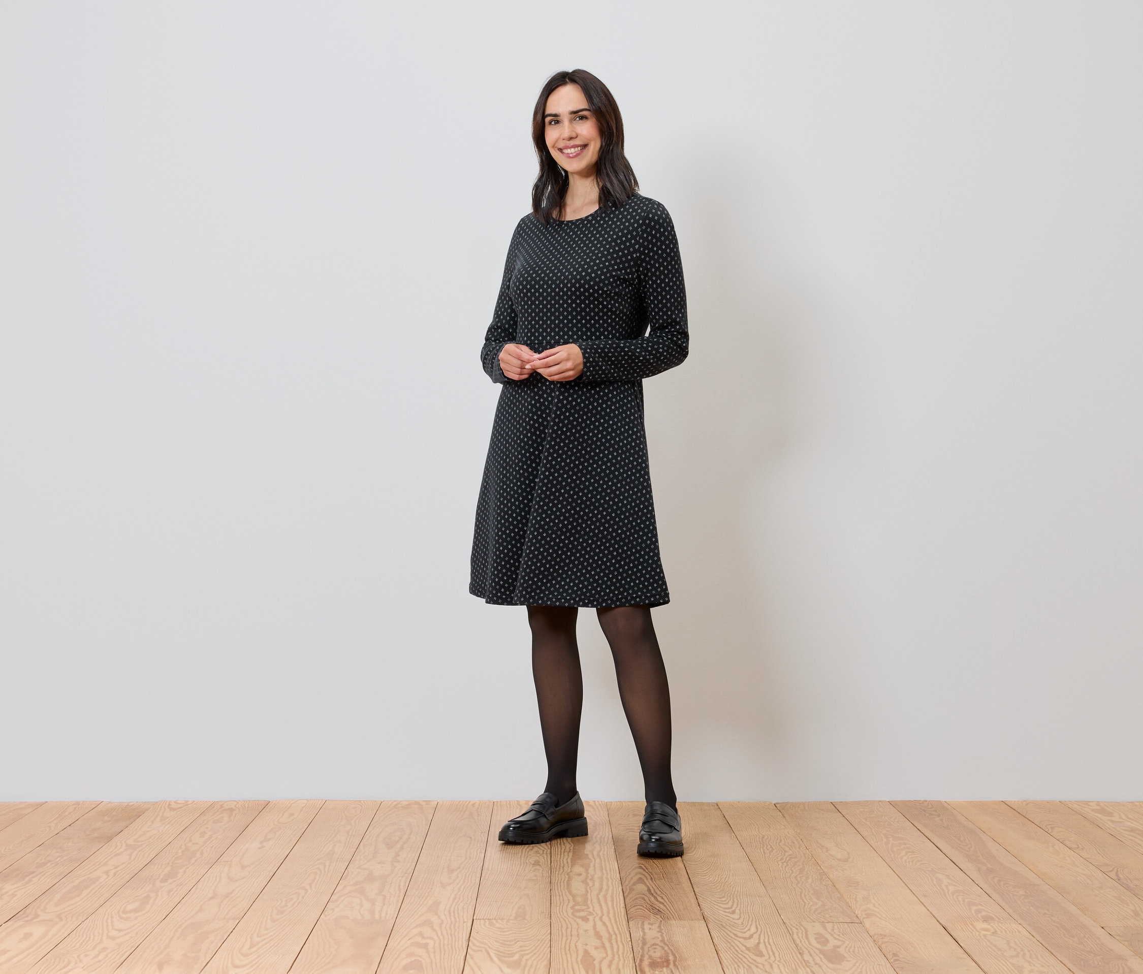 Frau steht und trägt ein glitzerndes Jacquard-Kleid.