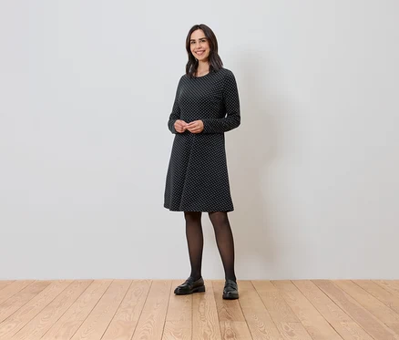 Frau steht und trägt ein glitzerndes Jacquard-Kleid.