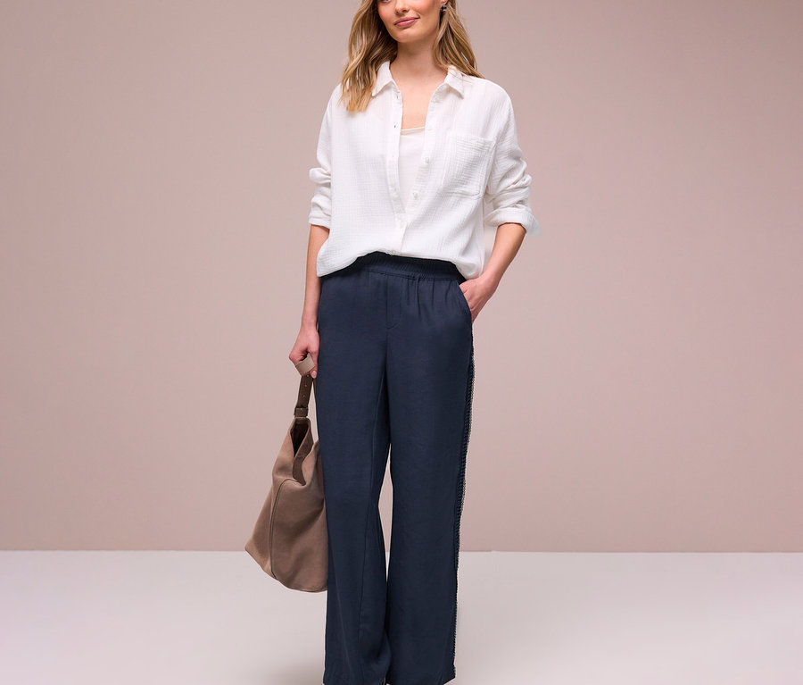 Frau in weißem Hemd und Street One Hose »Emee« mit beiger Tasche und Turnschuhen.